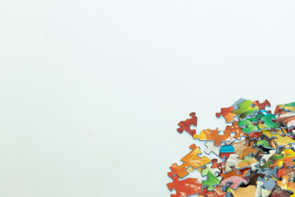 Home Scattered colorful puzzle pieces on a white background with copyspace.