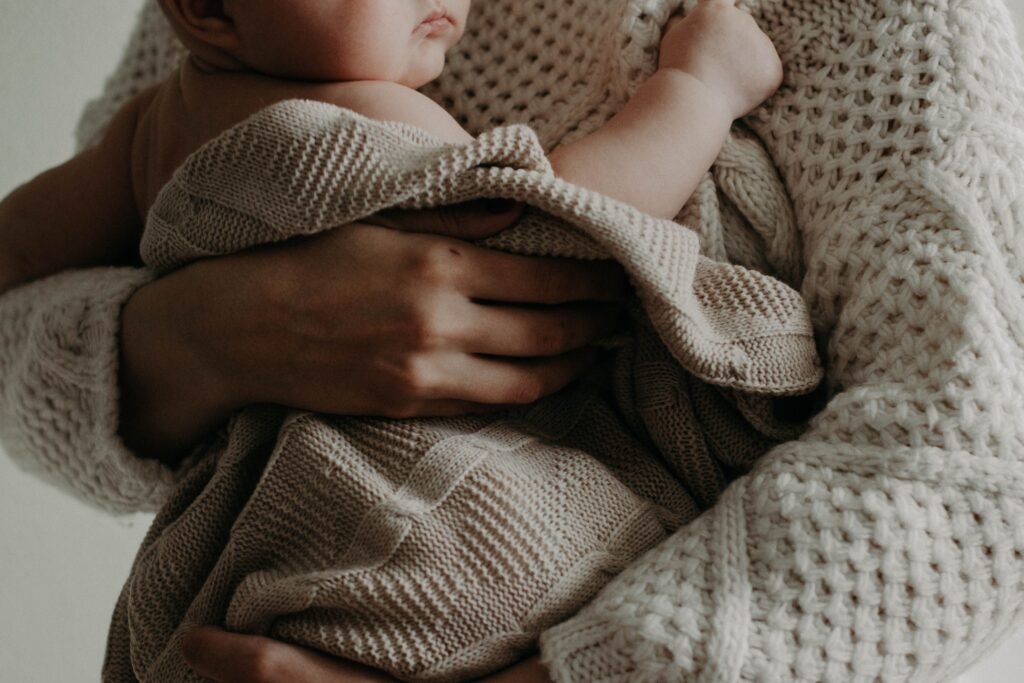 Postpartum Depression A tender moment of a mother holding her baby wrapped in a blanket, exuding warmth and care.