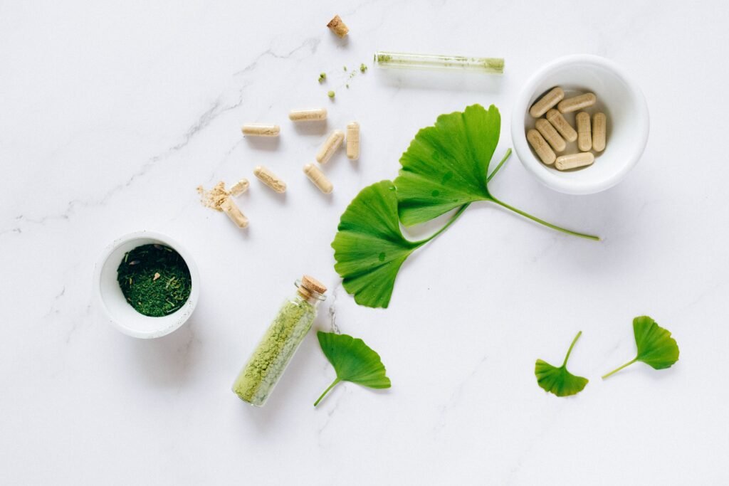 The Missing Piece in Mental Health Flat lay of herbal supplements with ginkgo leaves on marble surface, emphasizing natural health remedies.